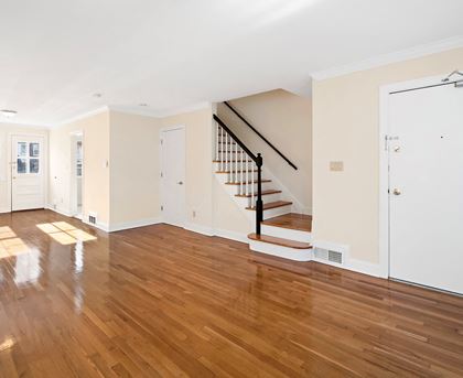 a living room with a staircase and a hard wood floor